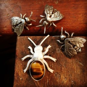 Three small sandcast silver bee pendants and a bee in progress with Tigereye gem